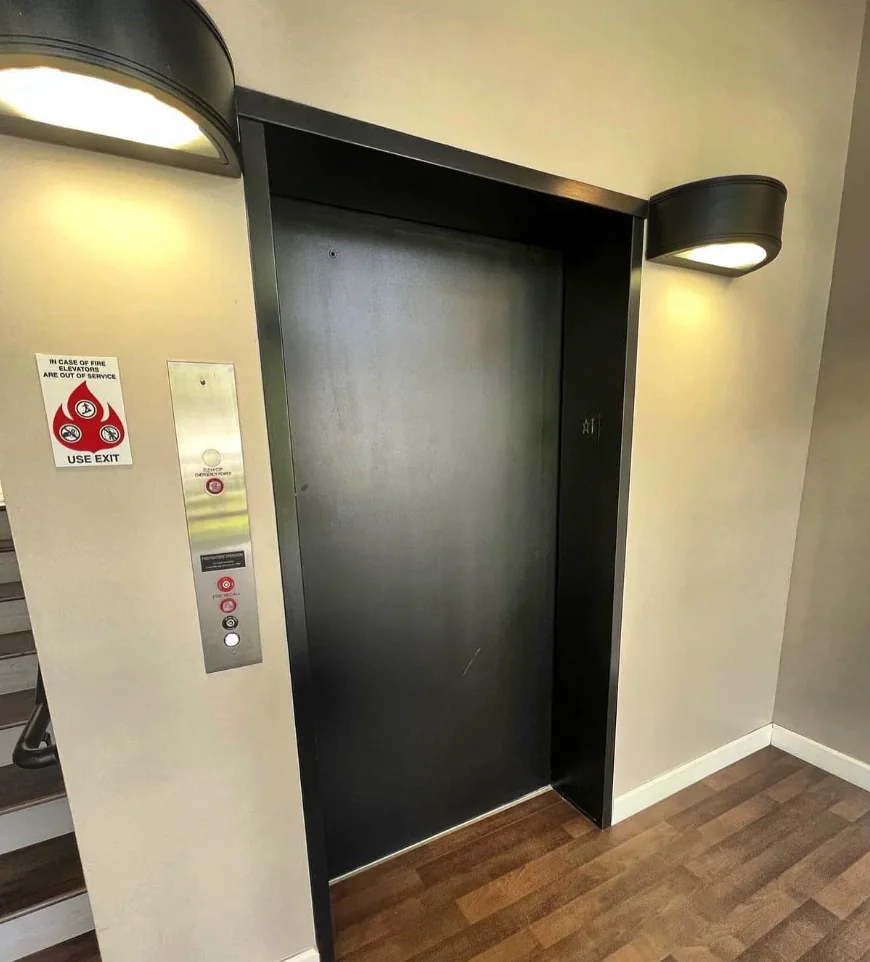 an empty room with a black door and wooden floors